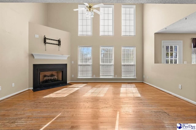 unfurnished living room featuring a towering ceiling and light wood-type flooring