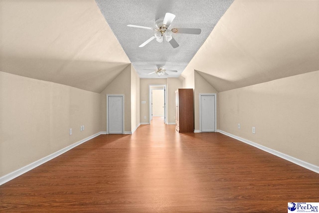 bonus room with vaulted ceiling, hardwood / wood-style floors, and a textured ceiling