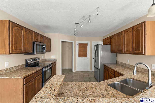 kitchen with stainless steel appliances, sink, a textured ceiling, and light tile patterned floors