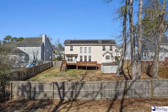 rear view of house featuring a storage unit, solar panels, and a deck