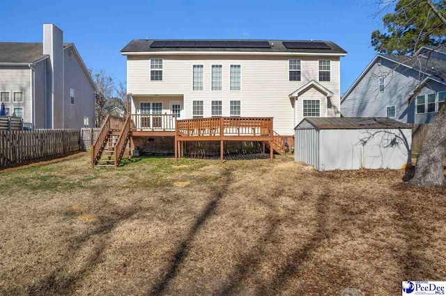 back of house with a wooden deck, a lawn, a shed, and solar panels