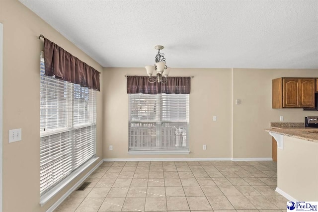 unfurnished dining area featuring a notable chandelier, light tile patterned floors, and a textured ceiling