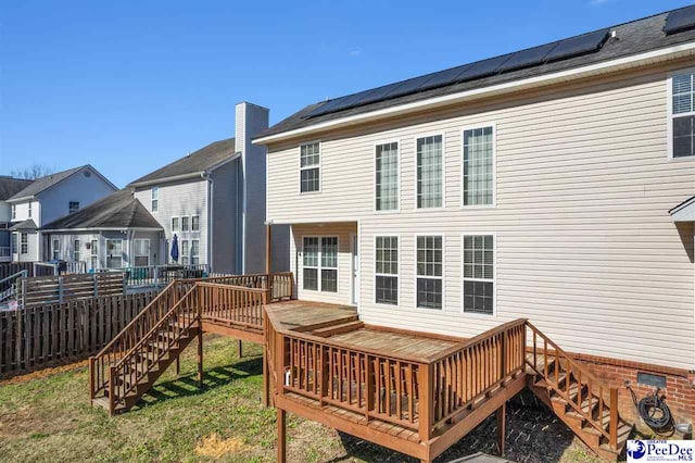 back of property featuring a wooden deck and solar panels