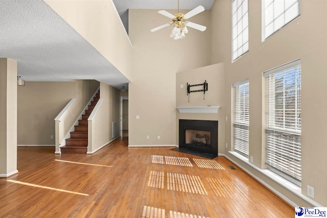 unfurnished living room with ceiling fan, hardwood / wood-style floors, and a textured ceiling