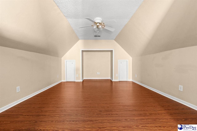 additional living space with ceiling fan, lofted ceiling, a textured ceiling, and dark hardwood / wood-style flooring