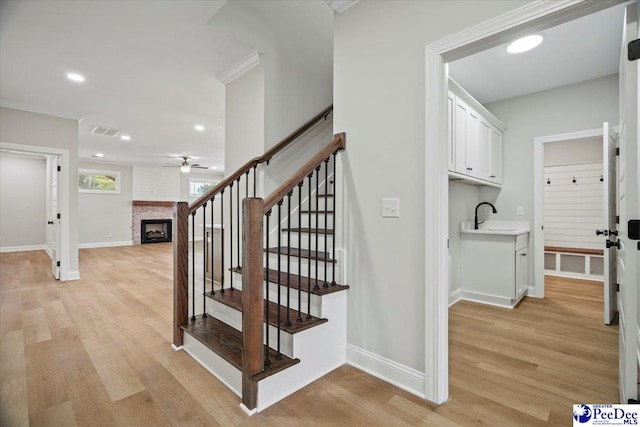 stairway featuring a fireplace, wood finished floors, visible vents, and baseboards