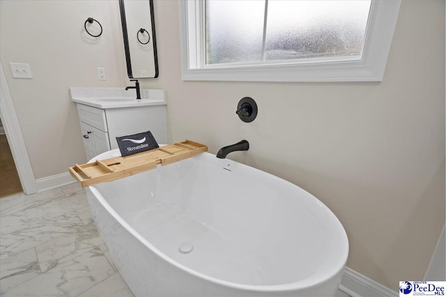 full bathroom with marble finish floor, a soaking tub, vanity, and baseboards