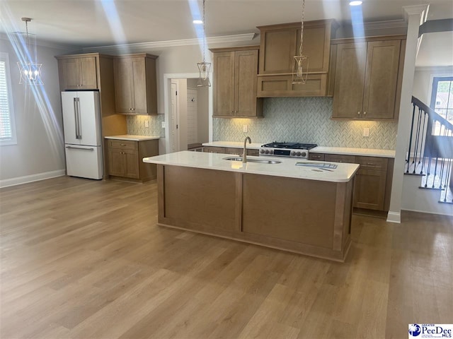 kitchen featuring crown molding, freestanding refrigerator, a sink, light wood-type flooring, and range