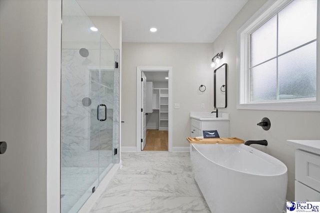 bathroom featuring a stall shower, baseboards, marble finish floor, a walk in closet, and vanity