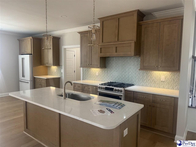 kitchen with decorative backsplash, gas range, ornamental molding, freestanding refrigerator, and a sink