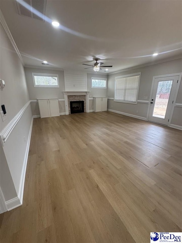 unfurnished living room featuring light wood-style floors, a fireplace, baseboards, and a ceiling fan