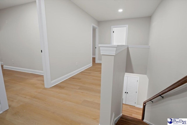 hall with baseboards, recessed lighting, an upstairs landing, and light wood-style floors