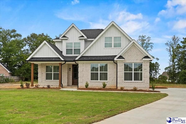 craftsman-style house featuring brick siding, a shingled roof, concrete driveway, board and batten siding, and a front yard