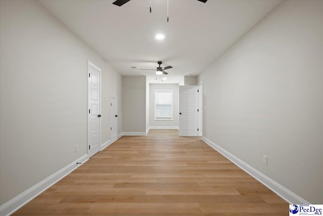 empty room featuring ceiling fan, light wood-style flooring, and baseboards