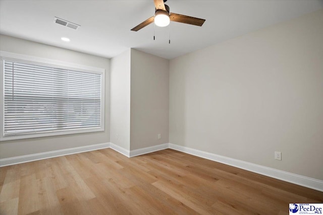 empty room with baseboards, visible vents, ceiling fan, and light wood-style flooring