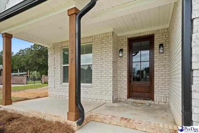 property entrance with covered porch and brick siding