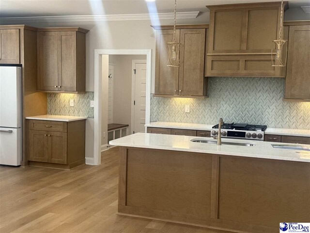 kitchen with tasteful backsplash, light wood-style flooring, hanging light fixtures, crown molding, and white fridge