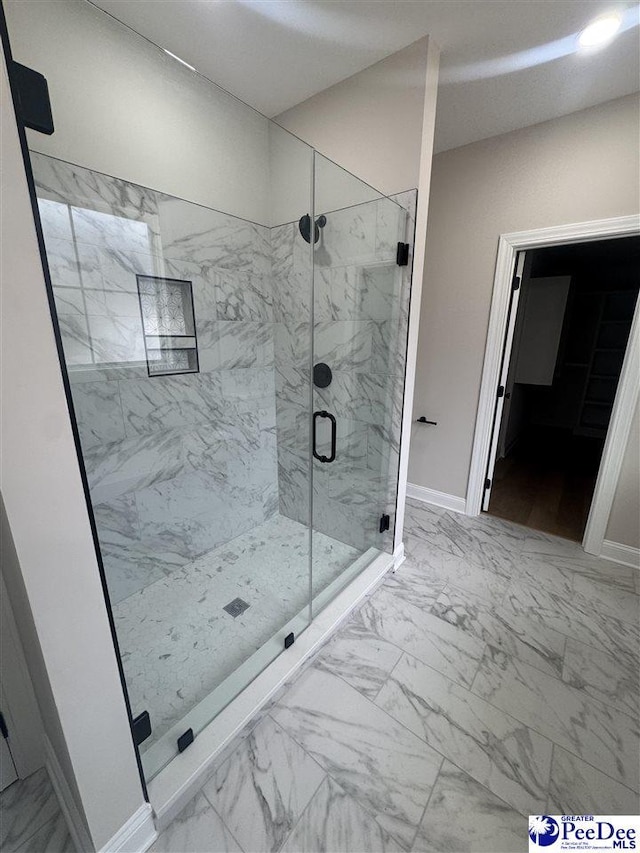 full bathroom with marble finish floor, a marble finish shower, and baseboards