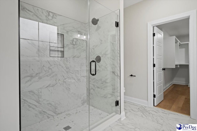 bathroom featuring marble finish floor, baseboards, and a marble finish shower