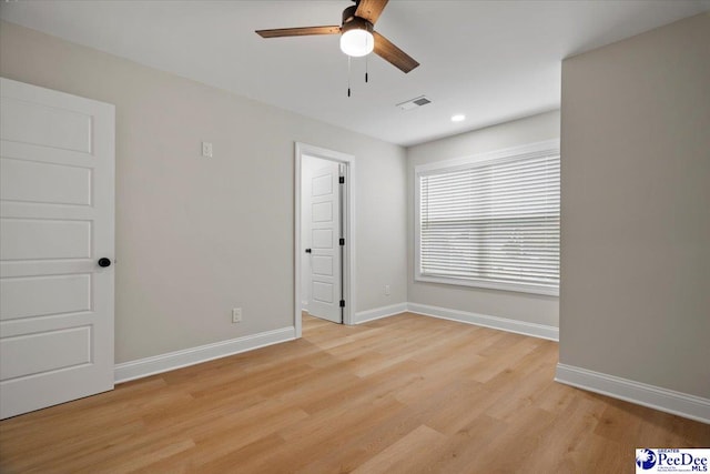 spare room featuring light wood-style floors, visible vents, baseboards, and a ceiling fan