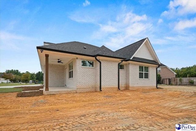 back of property with ceiling fan, a patio, brick siding, a shingled roof, and fence