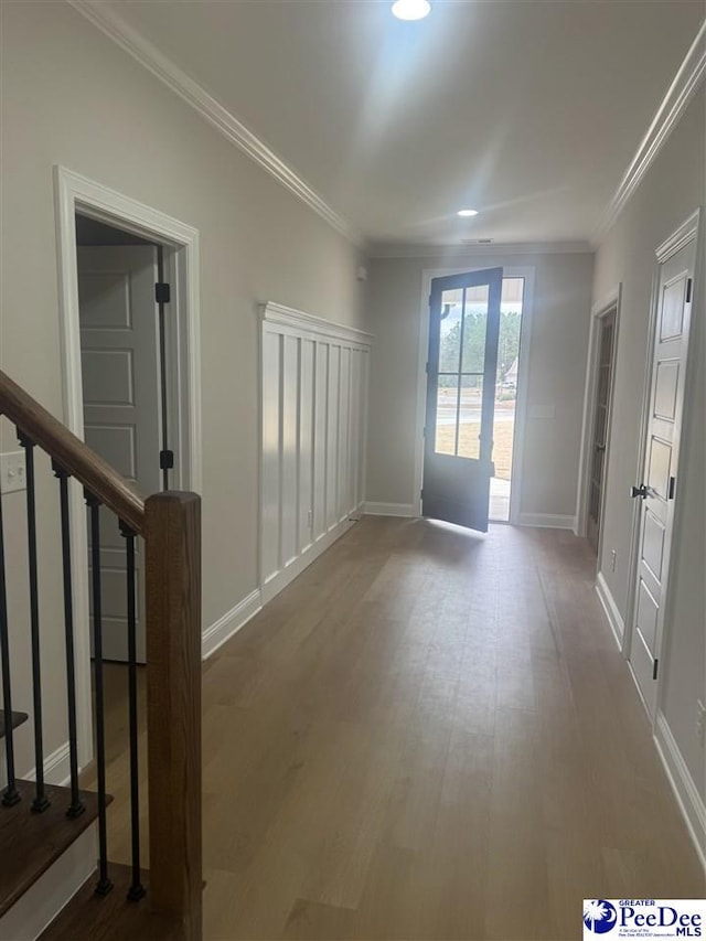 unfurnished room featuring wood finished floors, crown molding, and stairs