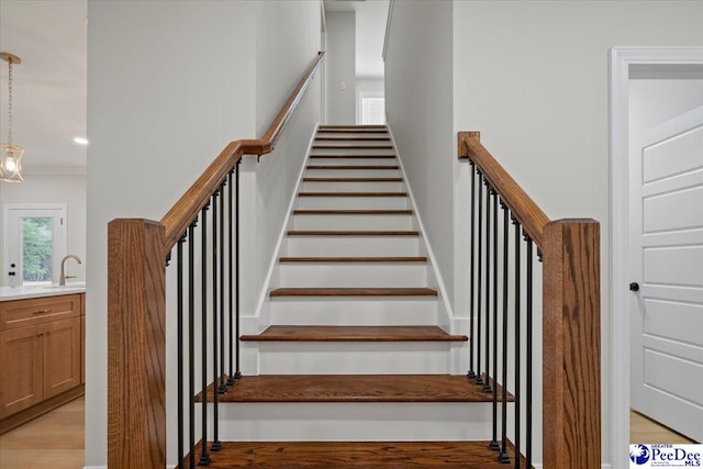 stairway with crown molding, wood finished floors, and recessed lighting