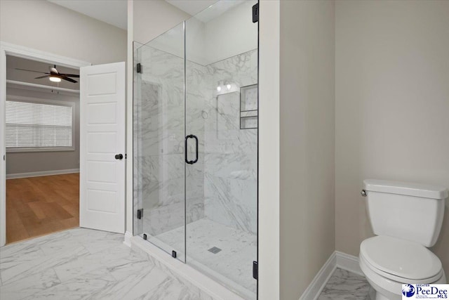 bathroom featuring toilet, marble finish floor, a marble finish shower, and baseboards