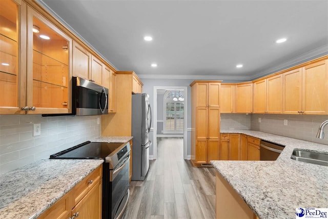 kitchen with light stone countertops, light wood-style flooring, ornamental molding, a sink, and appliances with stainless steel finishes