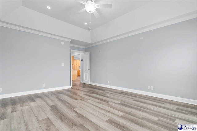 unfurnished room with baseboards, a tray ceiling, ornamental molding, wood finished floors, and a ceiling fan