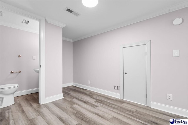 bathroom with visible vents, baseboards, wood finished floors, and ornamental molding