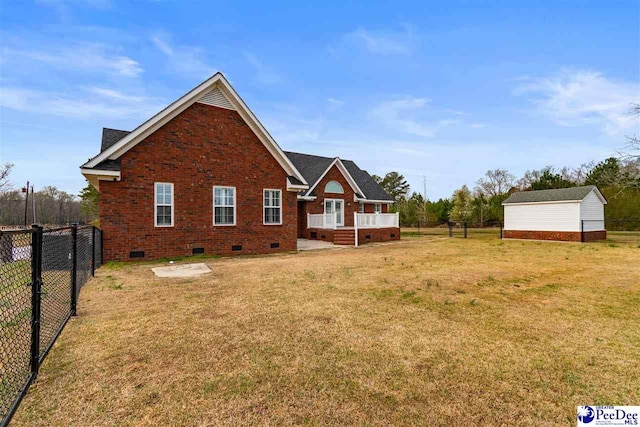 back of property featuring a lawn, a fenced backyard, an outdoor structure, crawl space, and brick siding