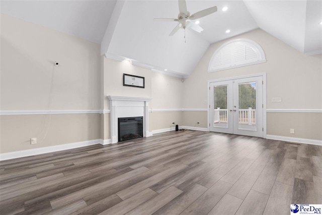 unfurnished living room with a ceiling fan, wood finished floors, baseboards, french doors, and a glass covered fireplace