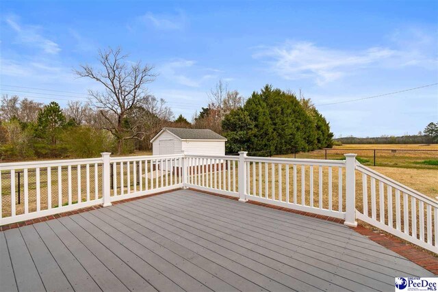 wooden deck featuring a storage shed, a detached garage, and an outdoor structure