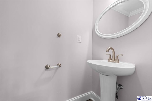 bathroom with ornamental molding, baseboards, and a sink