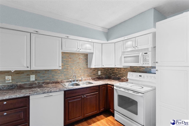 kitchen with white appliances, decorative backsplash, light wood-style floors, a sink, and white cabinetry