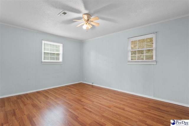spare room with a ceiling fan, visible vents, wood finished floors, and a textured ceiling