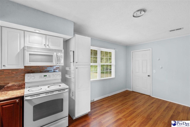 kitchen with a textured ceiling, visible vents, white appliances, and wood finished floors