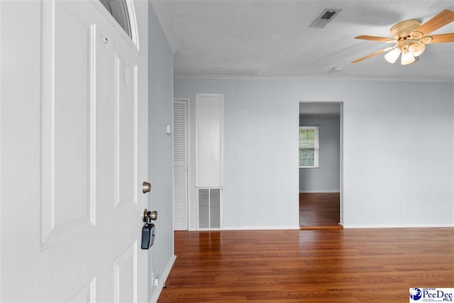 foyer entrance featuring visible vents, wood finished floors, a ceiling fan, and crown molding