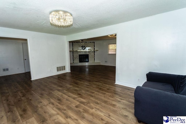 2318 Heron Dr, Florence, SC 29501 - living room featuring a stone fireplace, dark hardwood / wood-style floors, a textured ceiling, and a chandelier