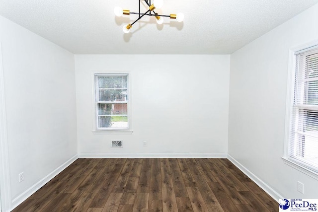 2318 Heron Dr, Florence, SC 29501 - empty room featuring dark wood-type flooring, a textured ceiling, and a notable chandelier