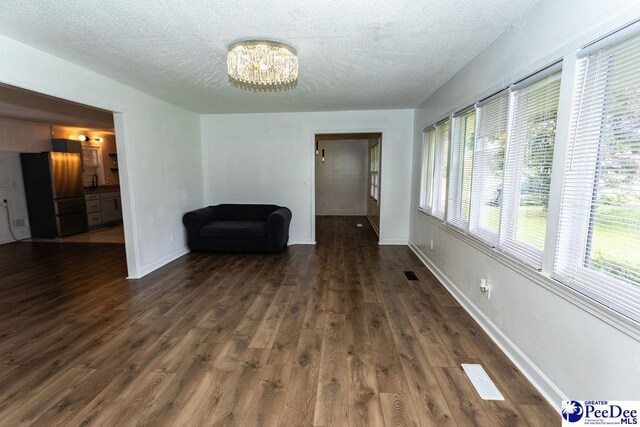 2318 Heron Dr, Florence, SC 29501 - unfurnished room with a notable chandelier, dark wood-type flooring, sink, and a textured ceiling