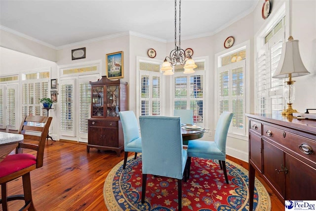 dining room with dark wood-type flooring, crown molding, and a notable chandelier