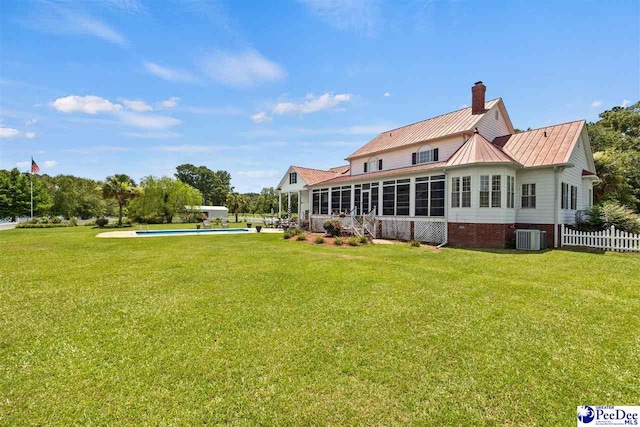 back of house featuring a sunroom, central air condition unit, and a lawn