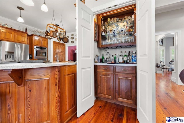 kitchen featuring dark wood-type flooring, sink, crown molding, hanging light fixtures, and stainless steel appliances