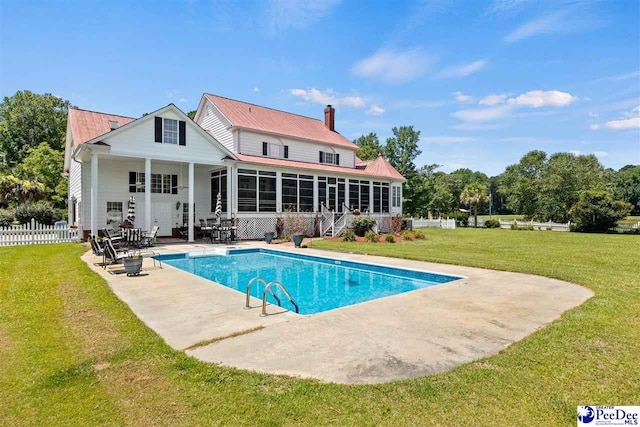 back of property featuring a lawn, a sunroom, and a patio area