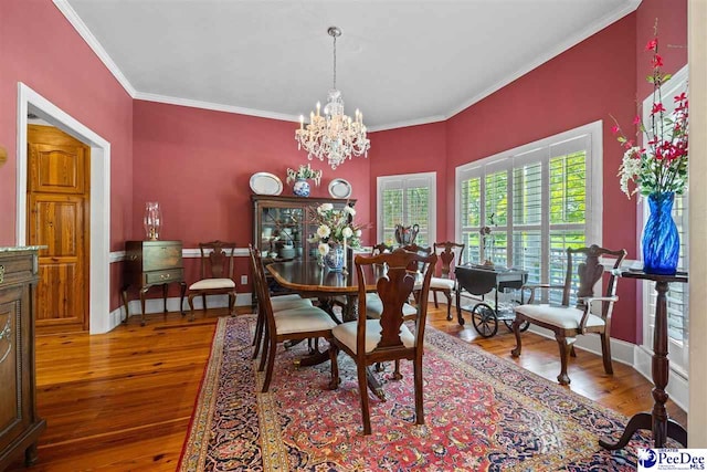 dining room with crown molding, wood-type flooring, and an inviting chandelier