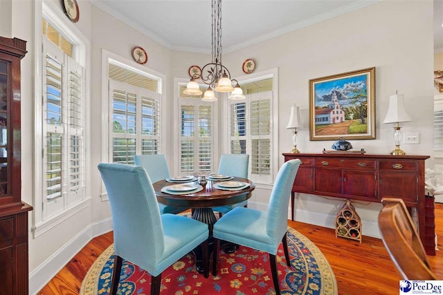 dining space featuring an inviting chandelier, hardwood / wood-style floors, and crown molding