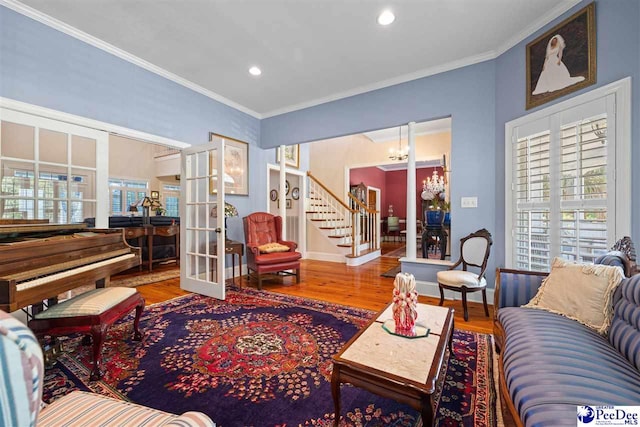 living room featuring wood-type flooring, ornamental molding, an inviting chandelier, and french doors