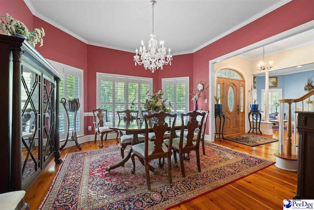 dining space with crown molding, wood-type flooring, and a notable chandelier